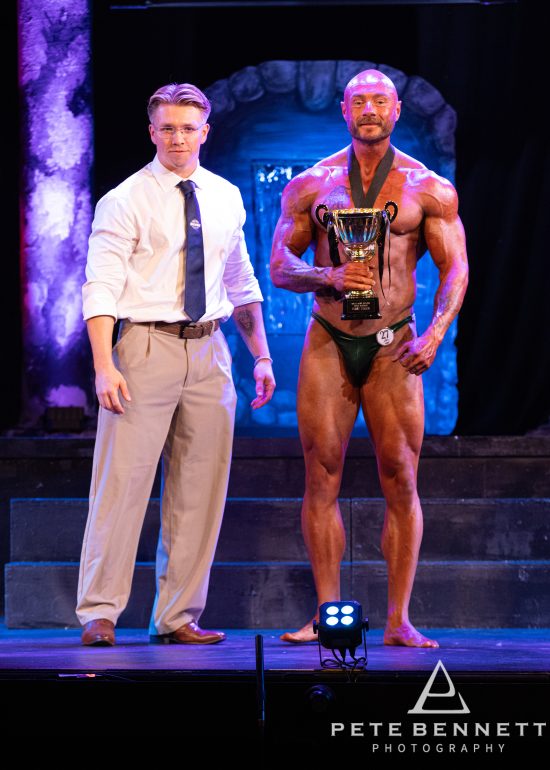 Men's class winner holding his trophy on stage at Devonport Playhouse, Plymouth